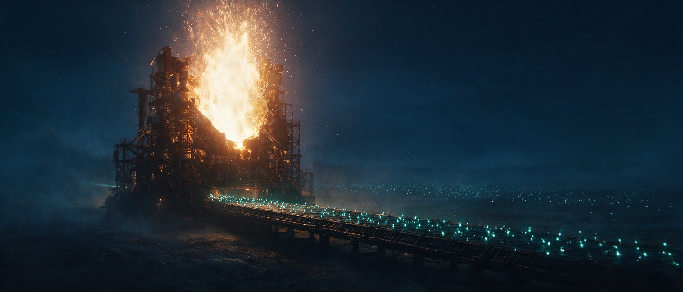 A colossal forge firing a single one-time blast of amber light, with a narrow conveyor of thousands of tiny cyan sparks running unbroken from its base to the far horizon.